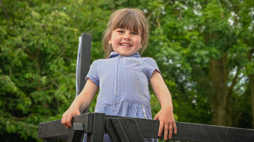 A student smiling with foliage in the background